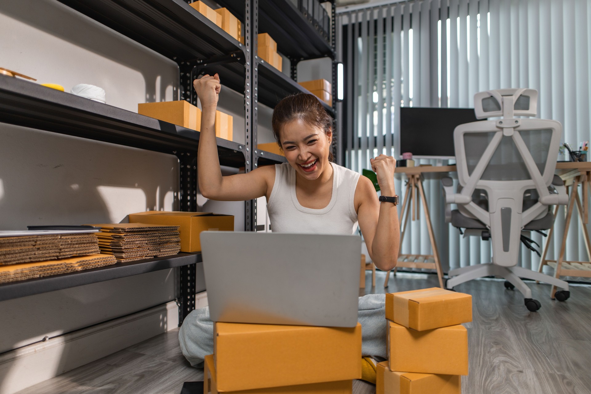 a small online business owner is feeling very happy because her business is successful, the entrepreneur shows her joy while she is in her warehouse, parcel, small business, joyful